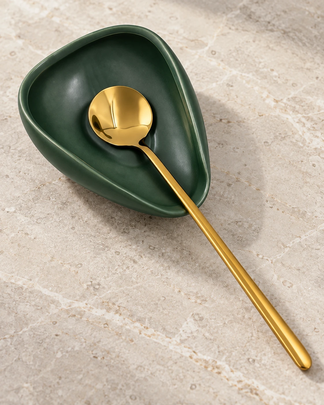 Dark green ceramic spoon rest with a polished gold coffee spoon